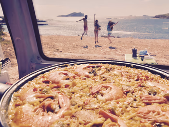 Paella en una camper van con la playa de fondo